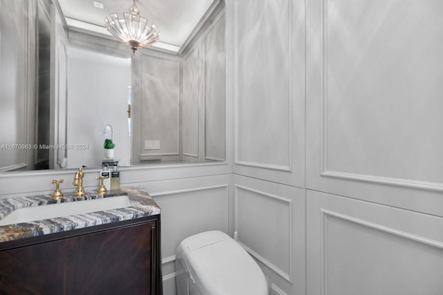 bathroom with toilet, a decorative wall, and vanity