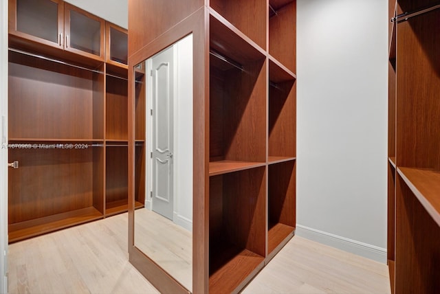 walk in closet with light hardwood / wood-style floors