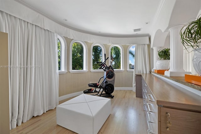 exercise room with ornate columns, light hardwood / wood-style floors, and crown molding