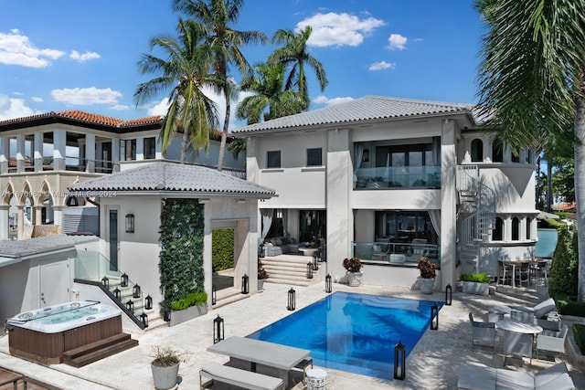 rear view of house featuring a swimming pool with hot tub, a patio area, and a balcony