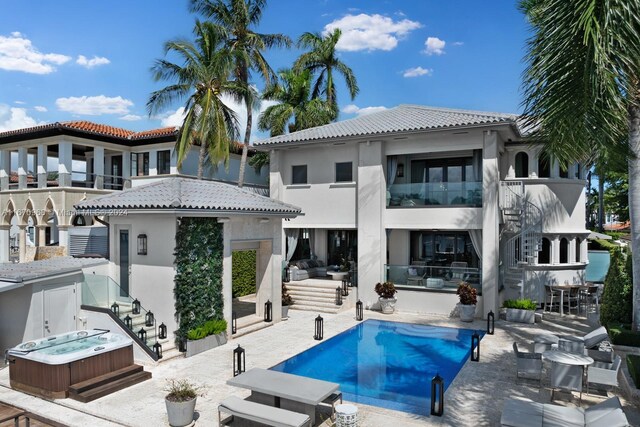 rear view of property with hot tub deck surround, stairway, stucco siding, and a tiled roof