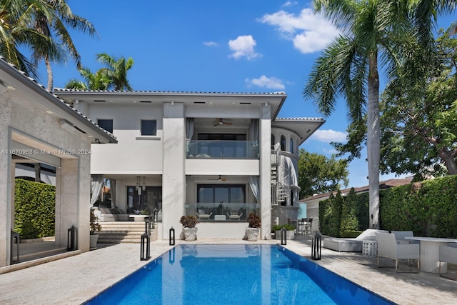 rear view of house with a fenced in pool, a patio area, ceiling fan, and a balcony