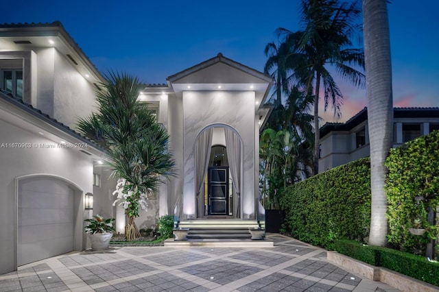 entrance to property featuring stucco siding and an attached garage