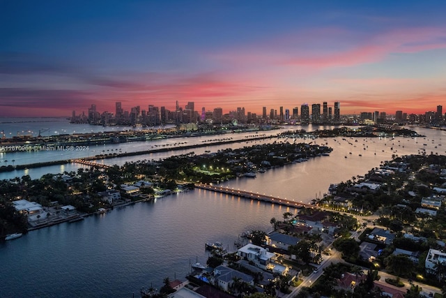 aerial view at dusk featuring a view of city and a water view