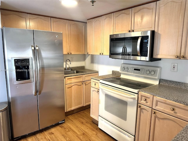 kitchen with light brown cabinets, sink, stainless steel appliances, and light hardwood / wood-style flooring