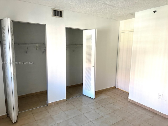 unfurnished bedroom featuring a textured ceiling and two closets