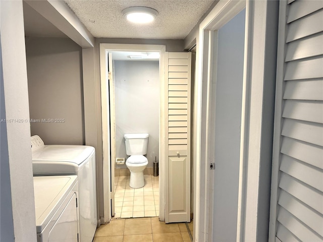 bathroom featuring washing machine and clothes dryer, tile patterned flooring, a textured ceiling, and toilet