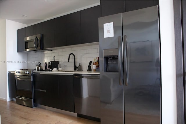 kitchen with decorative backsplash, stainless steel appliances, light wood-type flooring, and sink