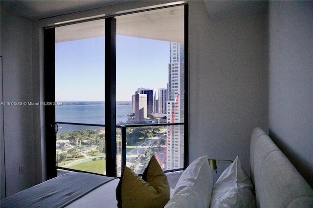 bedroom with floor to ceiling windows, a water view, and multiple windows