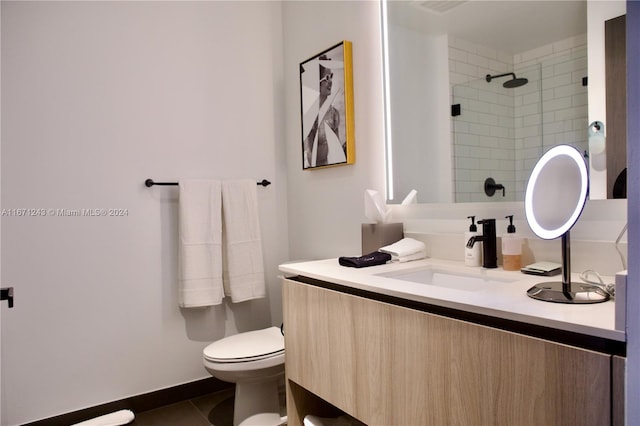 bathroom with a tile shower, vanity, toilet, and tile patterned floors