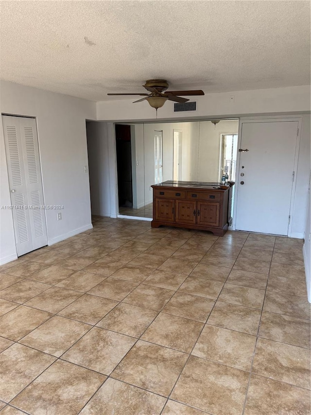 interior space featuring ceiling fan, a textured ceiling, and light tile patterned floors