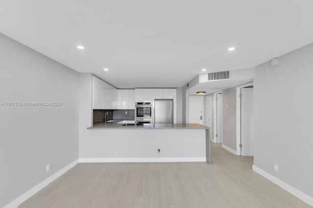 kitchen featuring stainless steel appliances, white cabinetry, decorative backsplash, sink, and kitchen peninsula