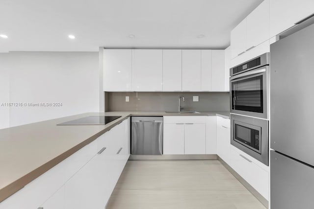 kitchen with white cabinetry, decorative backsplash, appliances with stainless steel finishes, and sink