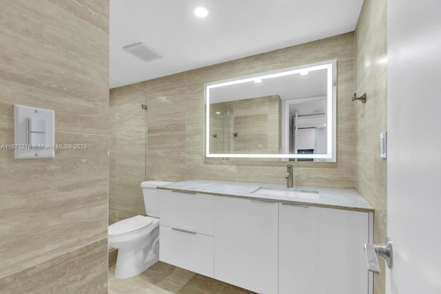 bathroom with toilet, vanity, tile walls, and walk in shower