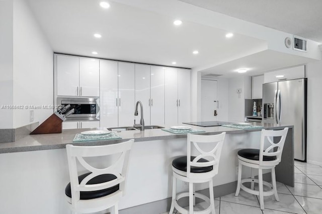 kitchen with visible vents, modern cabinets, stainless steel appliances, white cabinetry, and a sink