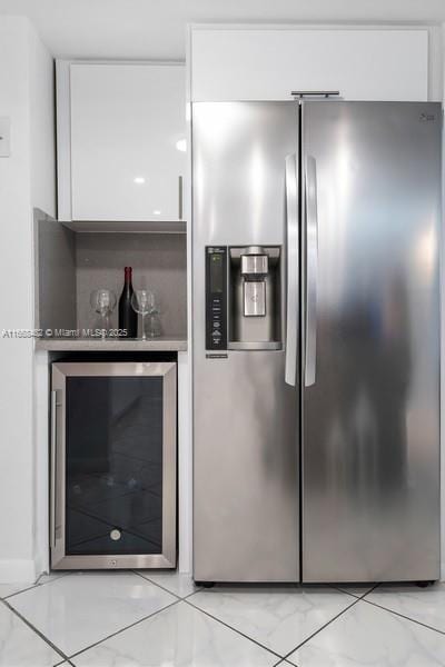 kitchen with light countertops, stainless steel fridge with ice dispenser, white cabinetry, beverage cooler, and marble finish floor