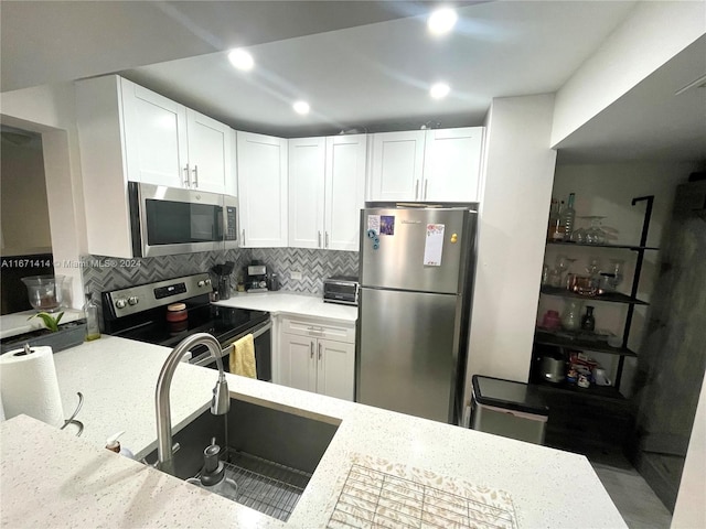 kitchen with stainless steel appliances, sink, tasteful backsplash, and white cabinetry