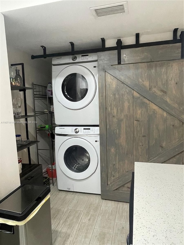 clothes washing area with stacked washer / drying machine and light hardwood / wood-style floors