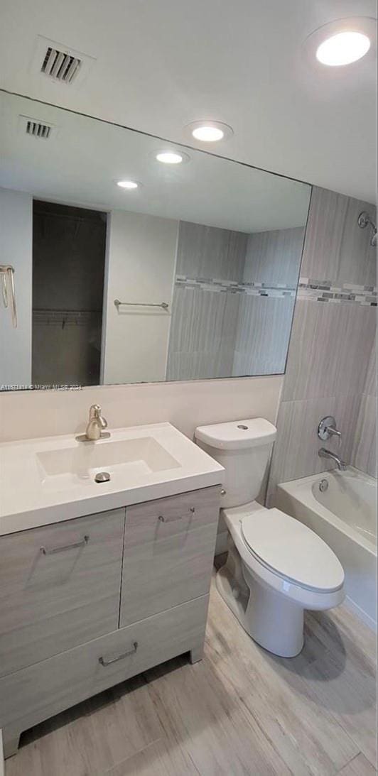 full bathroom featuring tiled shower / bath, vanity, and toilet