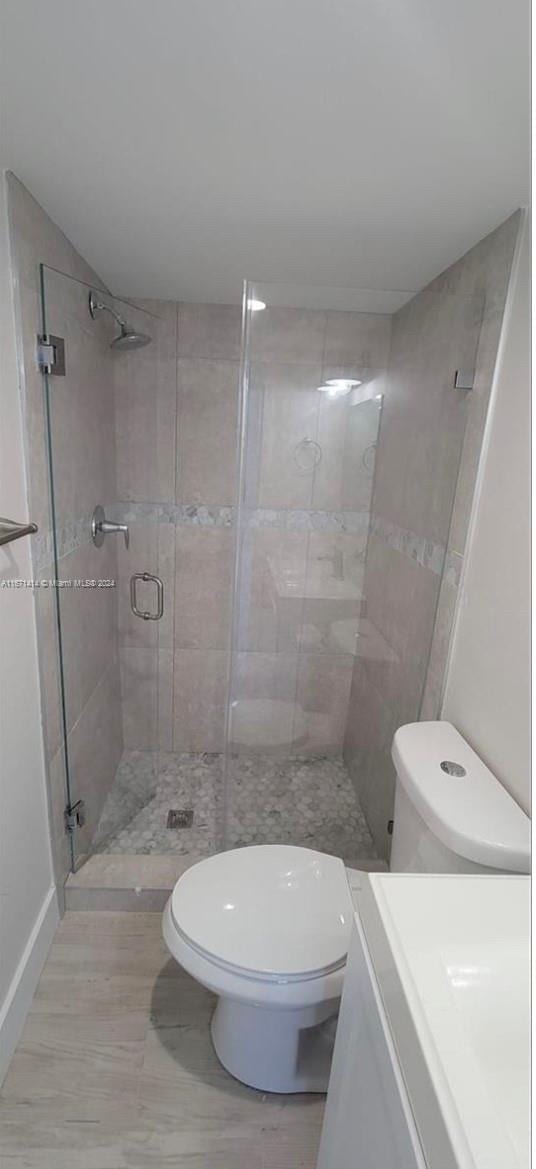 bathroom with a shower with door, vanity, and toilet