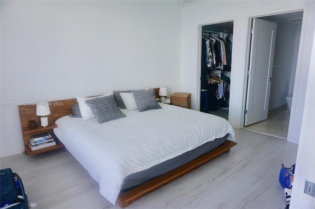 bedroom featuring light wood-type flooring, ensuite bath, a closet, and a walk in closet