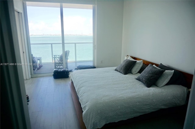 bedroom featuring hardwood / wood-style flooring and a water view