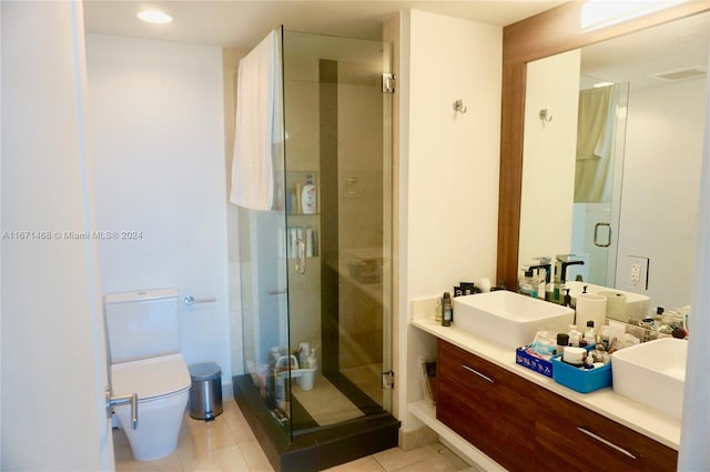 bathroom featuring tile patterned flooring, vanity, toilet, and a shower with door