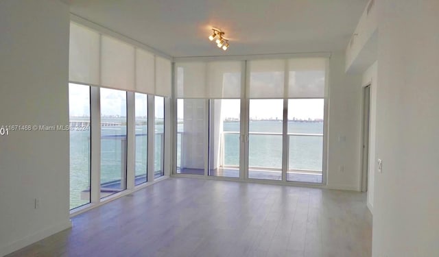 unfurnished room with wood-type flooring, a water view, and a wealth of natural light