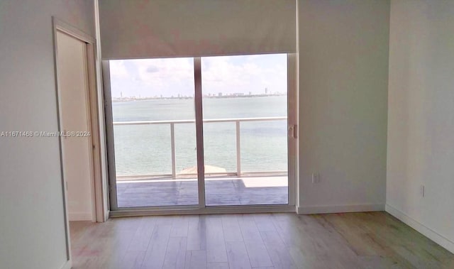 unfurnished room featuring light hardwood / wood-style floors and a water view