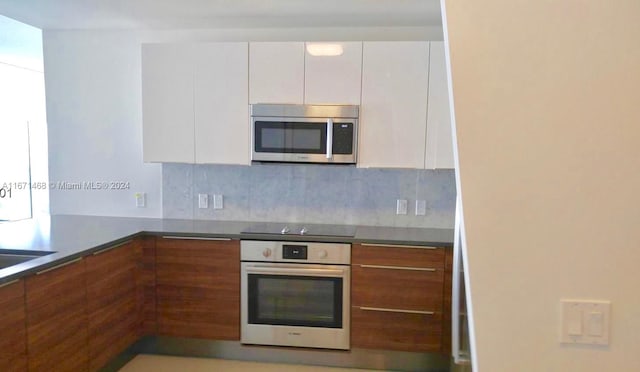 kitchen featuring appliances with stainless steel finishes, backsplash, and white cabinetry