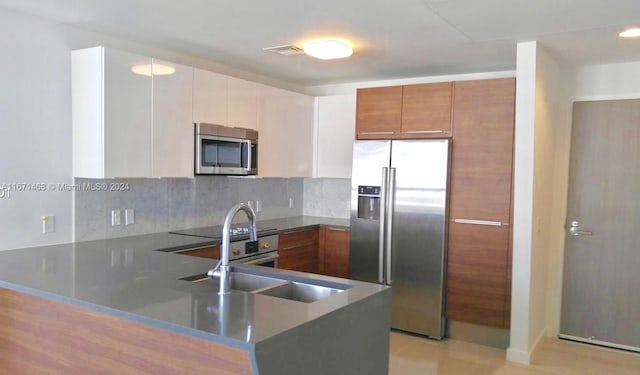 kitchen featuring stainless steel appliances, sink, tasteful backsplash, and white cabinetry