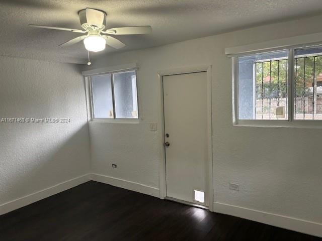 empty room featuring ceiling fan, a textured ceiling, and dark hardwood / wood-style flooring