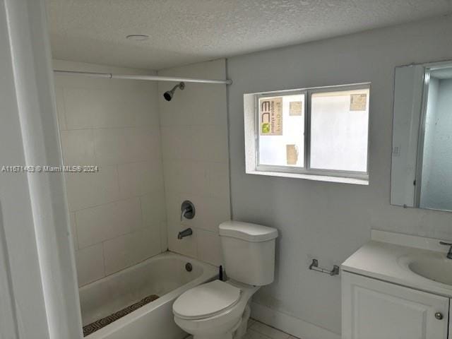 full bathroom featuring a textured ceiling, tiled shower / bath combo, vanity, and toilet