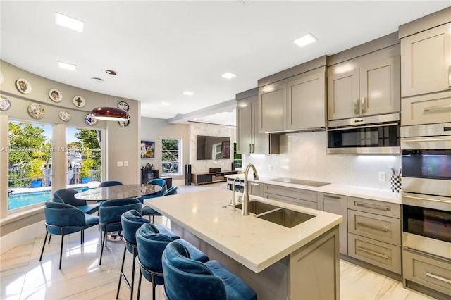 kitchen featuring sink, hanging light fixtures, stainless steel appliances, an island with sink, and a breakfast bar