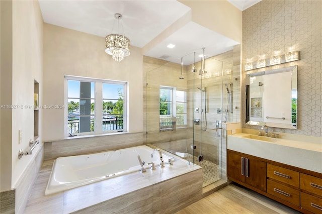 bathroom with an inviting chandelier, vanity, wood-type flooring, and shower with separate bathtub