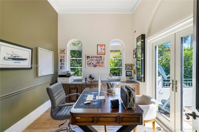 office space featuring ornamental molding, french doors, a healthy amount of sunlight, and light hardwood / wood-style flooring