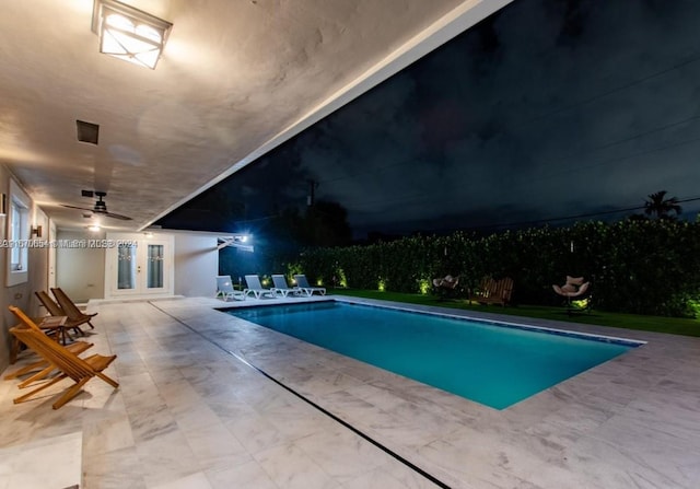 pool at night with ceiling fan, a patio area, and french doors