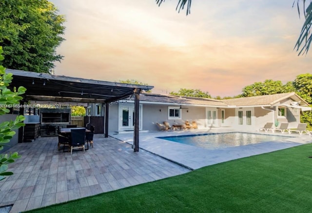 back house at dusk featuring a patio area and a yard