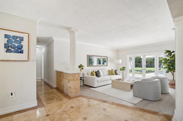 living room featuring baseboards, ornamental molding, a textured ceiling, french doors, and ornate columns