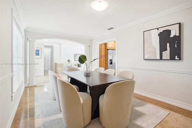 dining space with arched walkways, crown molding, ornate columns, visible vents, and baseboards