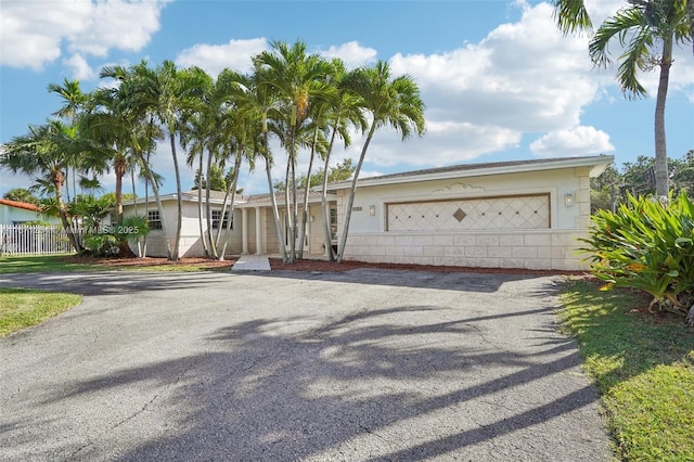 ranch-style house featuring fence, driveway, and an attached garage