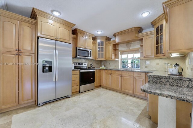 kitchen featuring decorative backsplash, light brown cabinetry, and appliances with stainless steel finishes