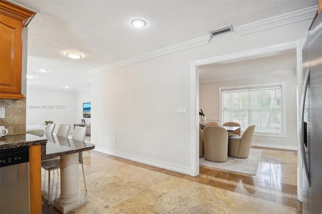 kitchen with crown molding, visible vents, baseboards, appliances with stainless steel finishes, and a kitchen breakfast bar