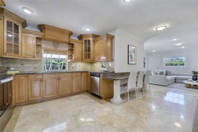 kitchen with appliances with stainless steel finishes, dark stone counters, backsplash, ornamental molding, and a breakfast bar area