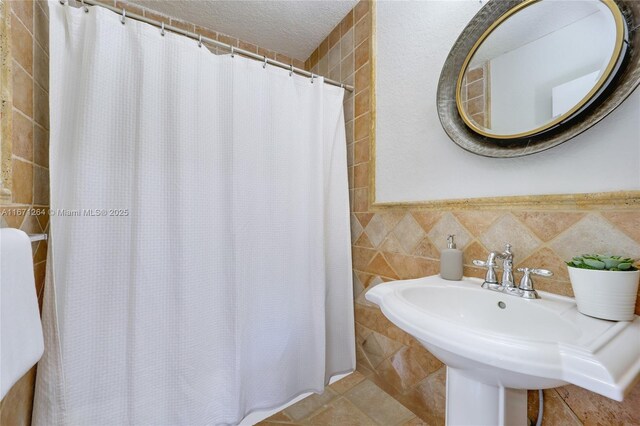 bathroom featuring sink, a textured ceiling, tile patterned flooring, and tile walls