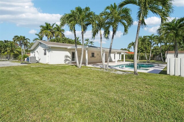 rear view of house featuring ac unit, a fenced in pool, a lawn, and a patio