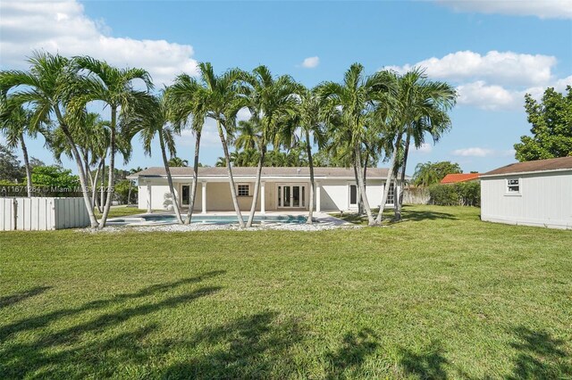 rear view of property featuring a fenced in pool, a yard, and an outdoor structure