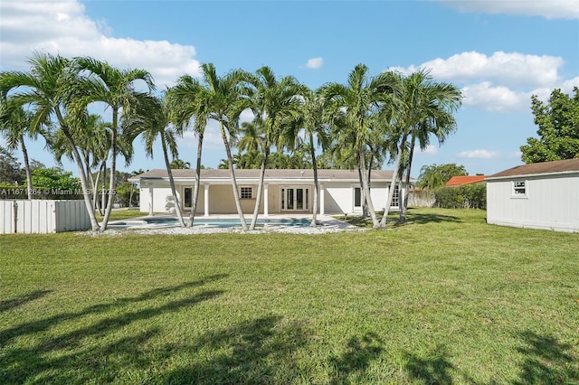 rear view of property with an outbuilding, a yard, fence, and a fenced in pool