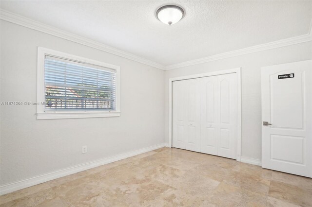 unfurnished bedroom featuring a textured ceiling, a closet, and crown molding