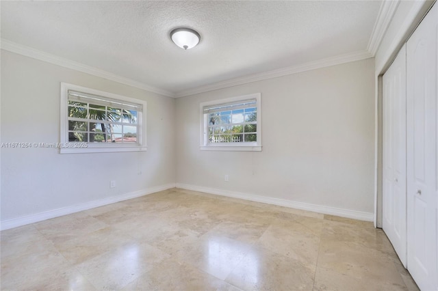 unfurnished bedroom with a textured ceiling, crown molding, a closet, and baseboards